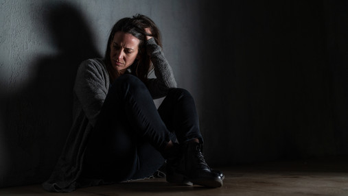 Frauenhaus Berlin - Interview mit Leitung Foto zum Thema Frauenhaus Berlin: Zu sehen ist eine verzweifelte Frau, die auf dem Boden sitzt, den Rücken an die Wand gelehnt.