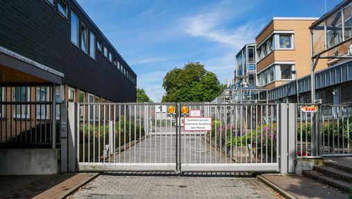 Foto zum Thema "Maßregelvollzug Moringen": Zu sehen ist die Zufahrt zum Gelände, die durch ein hohes Gatter versperrt ist.