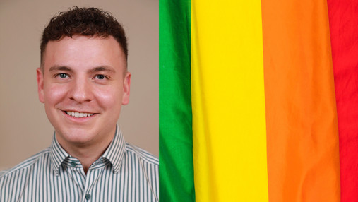 AG Diversity der dbb jugend - Alexander Seeger über multikulturelle Vielfalt Das Foto zeigt Alexander Seeger, Mitglied der AG Diversity der dbb jugend, neben einer Regenbogenflagge.