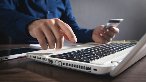 Onlinebanking mit Köpfchen Zu sehen ist ein Mann, der am Laptop sitzt und seine Kreditkartendaten eintippt.