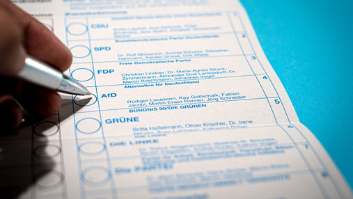 Warum wählen junge Leute die AfD? - Interview mit Klaus Hurrelmann Foto zum Thema warum wählen junge Leute AfD: Zu sehen ist ein Wahlzettel, darüber eine Hand von jemanden, der gerade sein Kreuzchen setzt.