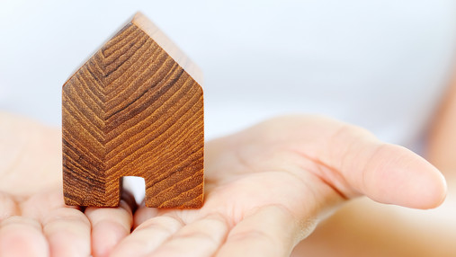 Vom Elternhaus in die eigenen vier Wände Zu sehen sind Hände, die Handflächen nach oben gewendet. Darauf steht ein Modellhäuschen.