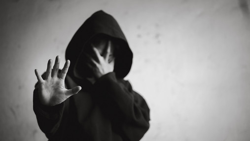 Was ist eine Sucht - Kriterien, die als Alarmzeichen gelten Foto zum Thema Sucht-Kriterien: Zu sehen ist eine verzweifelte Person mit einem Hoodie, die die Hand abweisend nach vorne streckt.