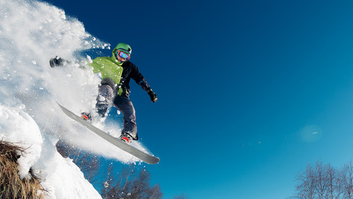 Urlaub ohne böse Überraschungen snowboarder is jumping with snowboard from snowhill