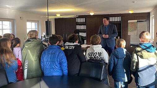 Foto zum Thema "wie wird man Bürgermeister": Zu sehen ist Joachim Weschbach in seinem Büro, Schülerinnen und Schüler hören ihm zu.