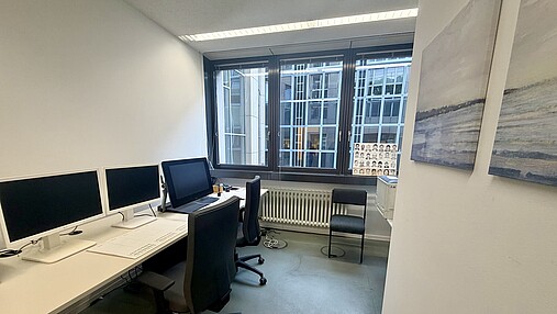 Foto zum Thema "wie wird man Phantombildzeichner*in": Zu sehen ist ein Büro, in dem Phantombilder gezeichnet werden. Es ist schlicht, es gibt einen Schreibtisch mit mehreren Displays.