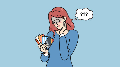 Gut vorbereitet zum Kredit Zu sehen ist eine Frau, die ratlos auf ihre Kreditkarten schaut, die sie wie ein Fächer in der Hand hält.