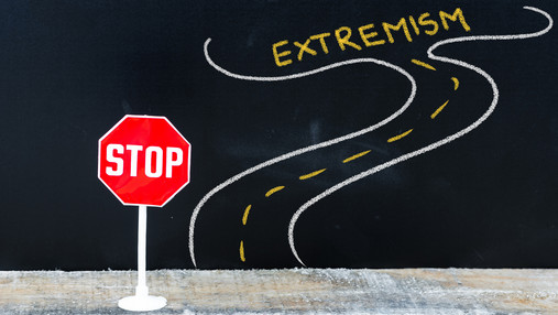 FES Mitte-Studie - Zwölf Prozent der jungen Menschen teilen rechtsextremes Weltbild Foto zum Thema FES Mitte-Studie: Zu sehen ist ein Stoppschild an einer Straße, an deren Ende ein Extremismus-Schriftzug erscheint.