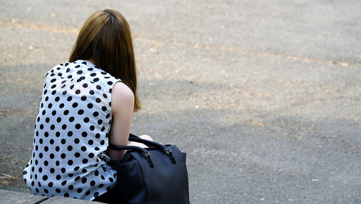 Kinder- und Jugendtelefon - Hilfe bei Einsamkeit Foto zum Thema "Kinder- und Jugendtelefon": Zu sehen ist ein Mädchen, das geknickt auf einem Kantstein sitzt und den Rücken zugewandt hat.