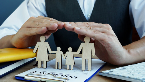 Wichtige Policen zuerst! Agent protects family figures. Life Insurance policy on a desk.